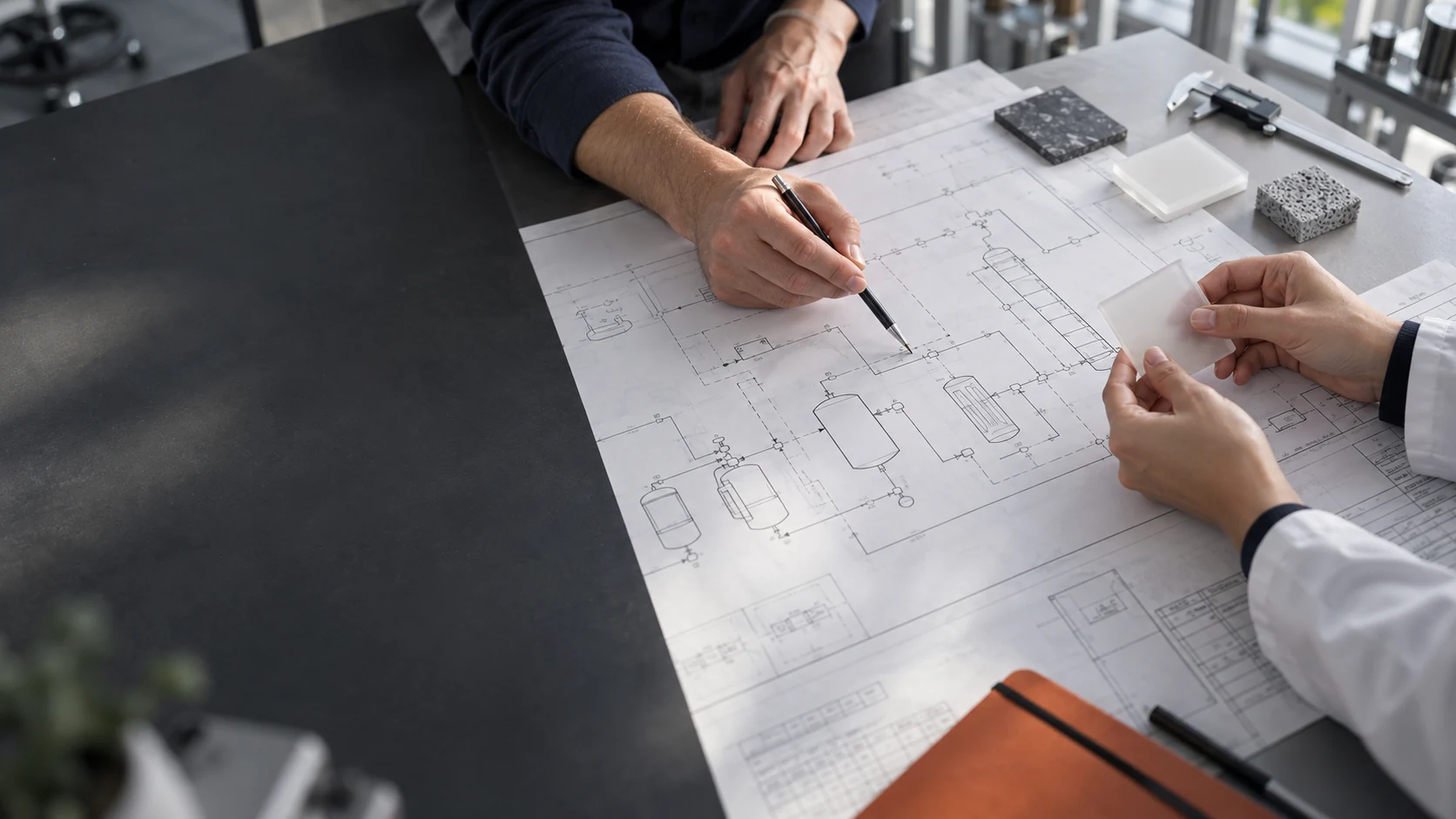 Illustrative technical collaboration reviewing material samples and a process drawing